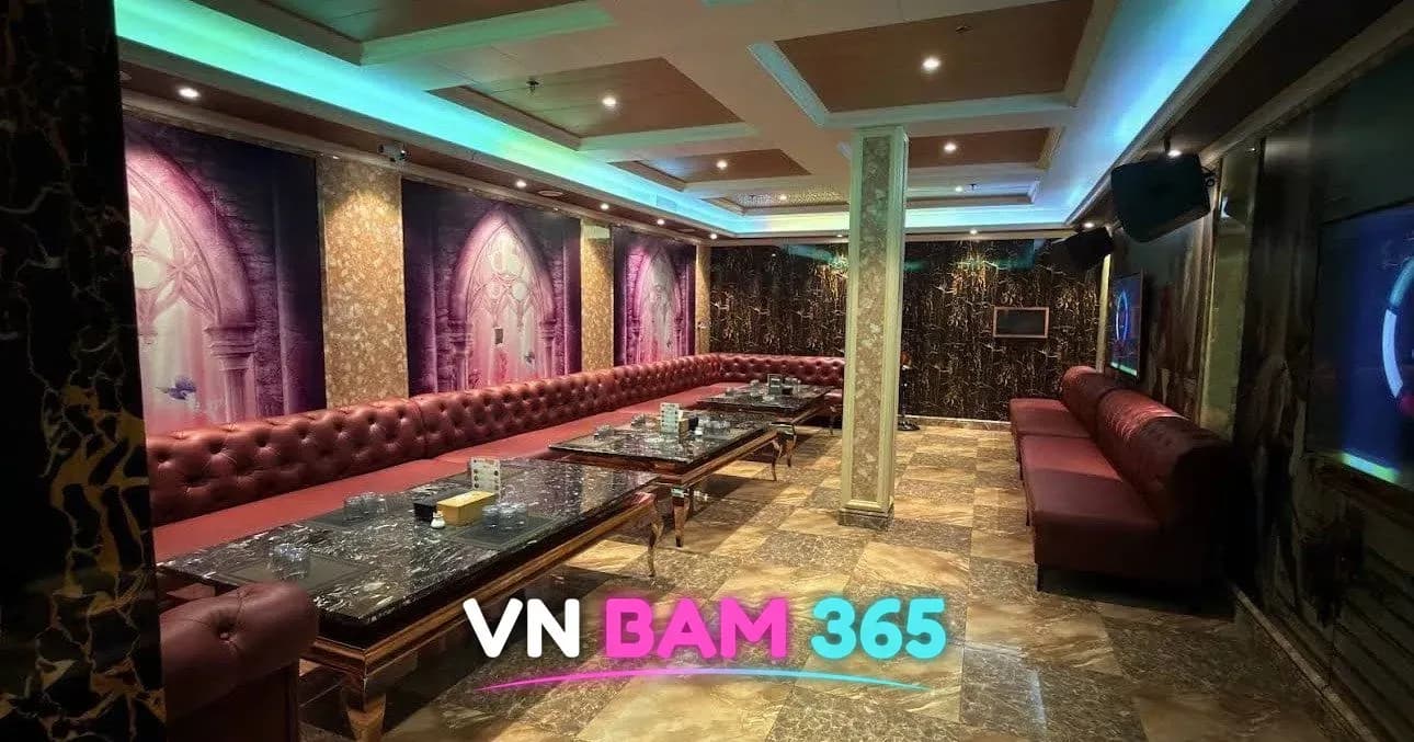 다낭 아우디 가라오케 VIP 룸을 반대쪽에서 본 모습, 붉은 소파와 대리석 테이블이 길게 이어짐