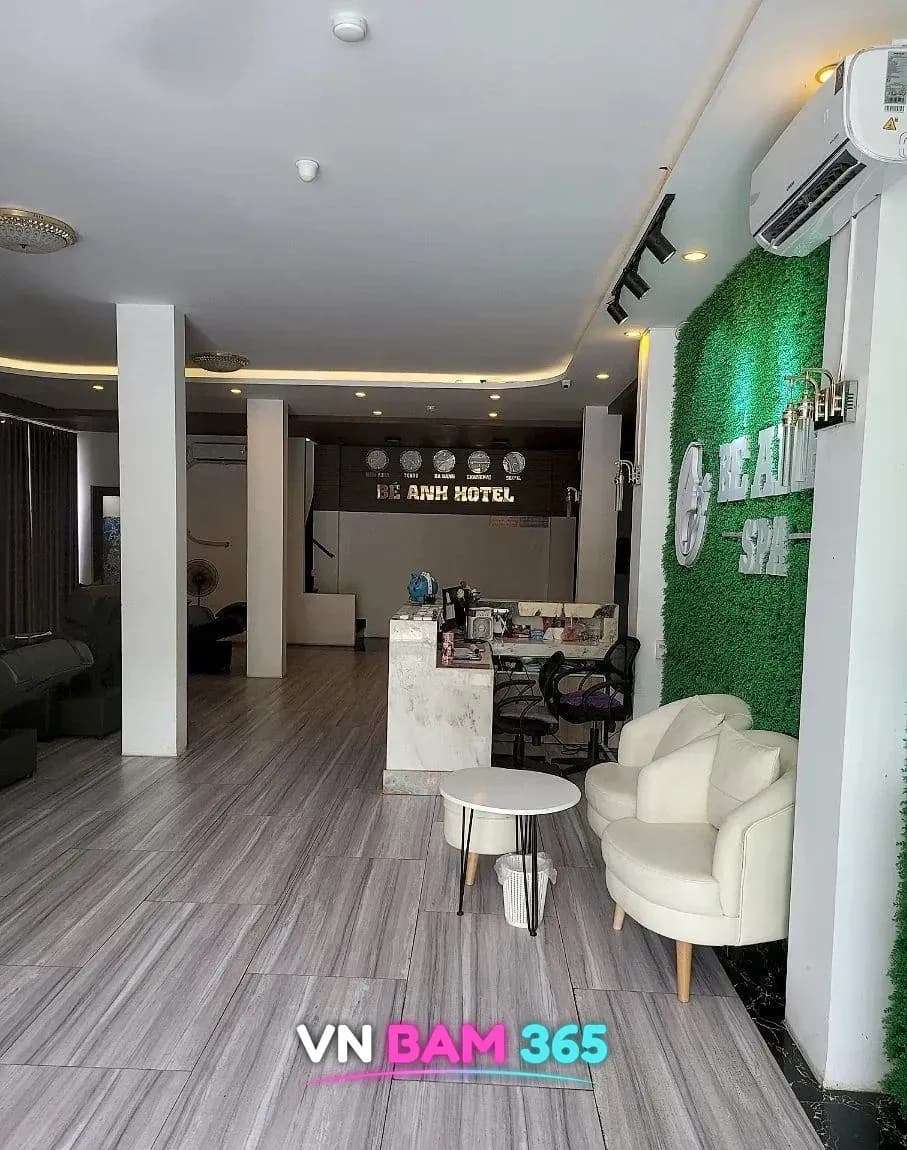 다낭 베안스파 1층 로비, BÉ ANH SPA 로고가 붙은 인조잔디 녹색 벽과 흰 원형 의자, 안쪽 Bé Anh Hotel 리셉션