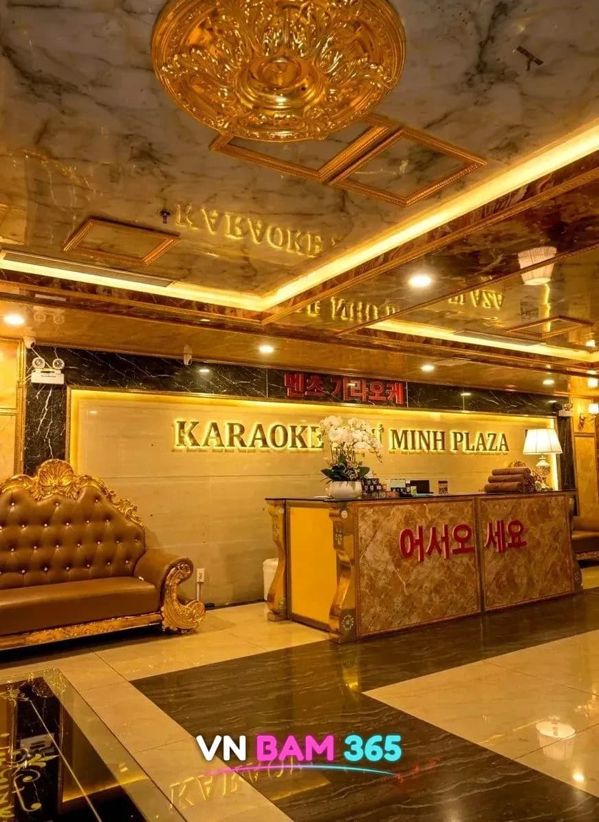 다낭 벤츠 가라오케가 있는 Nhu Minh Plaza 건물 로비, 금색 몰딩 천장과 KARAOKE NHU MINH PLAZA 간판, 어서오세요 안내 데스크