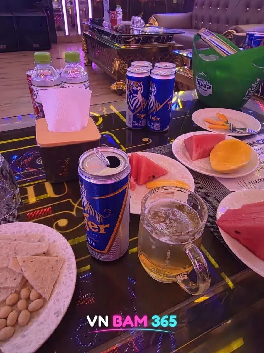 다낭 벤츠 가라오케 룸 테이블의 수박·망고 과일 접시와 타이거 맥주, 과자 안주