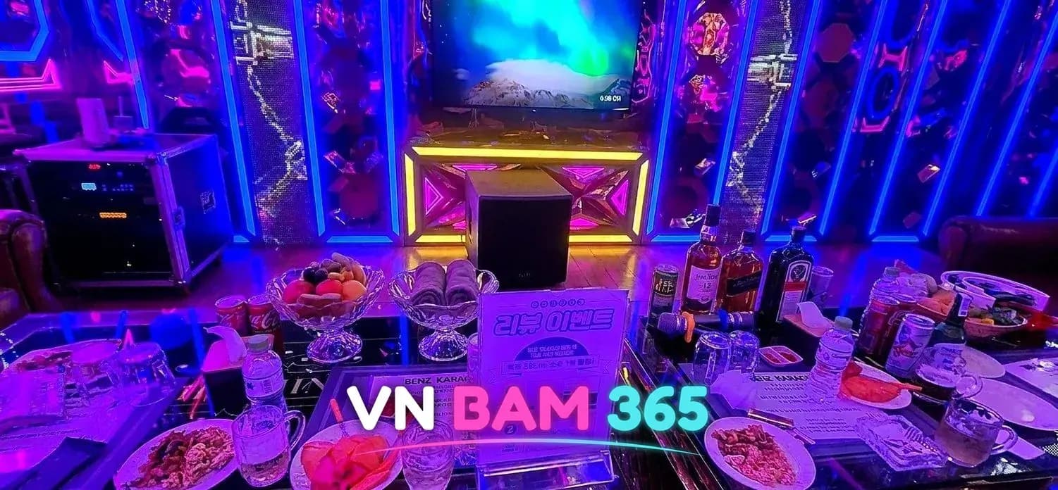 다낭 벤츠 가라오케 룸 테이블, 과일 접시와 안주, 위스키 병이 놓인 유리 테이블과 파란 네온 벽