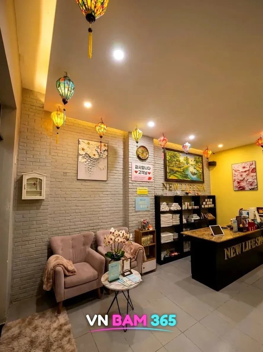 다낭 뉴라이프 스파 로비, 베트남 등롱 아래 소파 두 개와 NEW LIFE SPA 리셉션 카운터