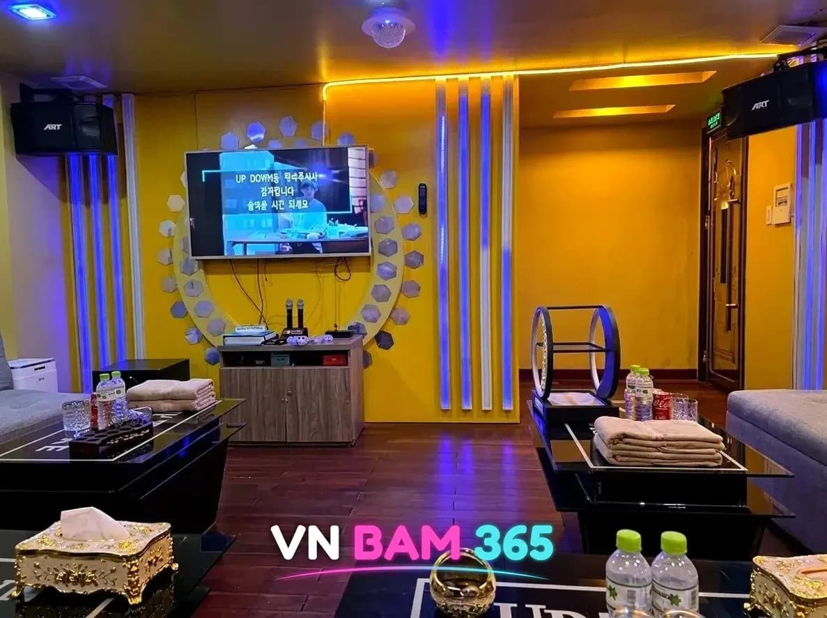 다낭 업타운 가라오케 룸, 노란 벽과 파란 세로 조명, 원형 조명 장식과 노래방 화면
