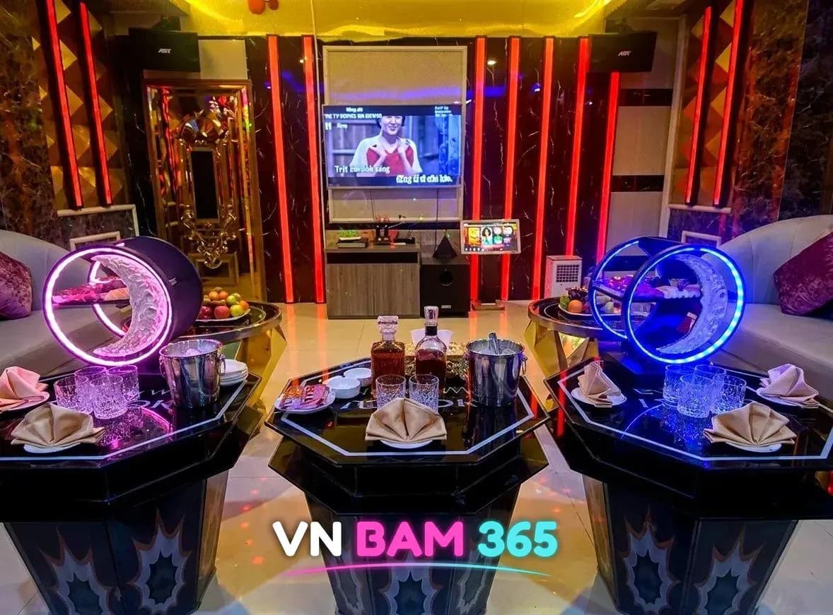 다낭 업타운 가라오케 룸, 붉은 세로 조명 벽과 원형 조명 장식, 위스키와 아이스버킷이 놓인 팔각 테이블