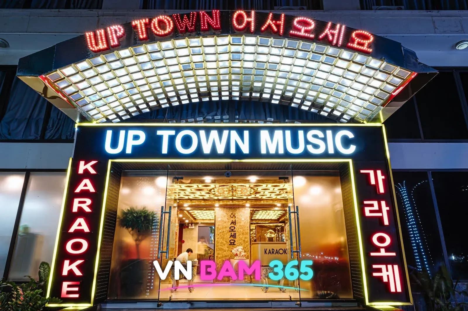 다낭 업타운 가라오케 입구, UP TOWN MUSIC 간판과 KARAOKE·가라오케 세로 네온, 「어서오세요」 차양