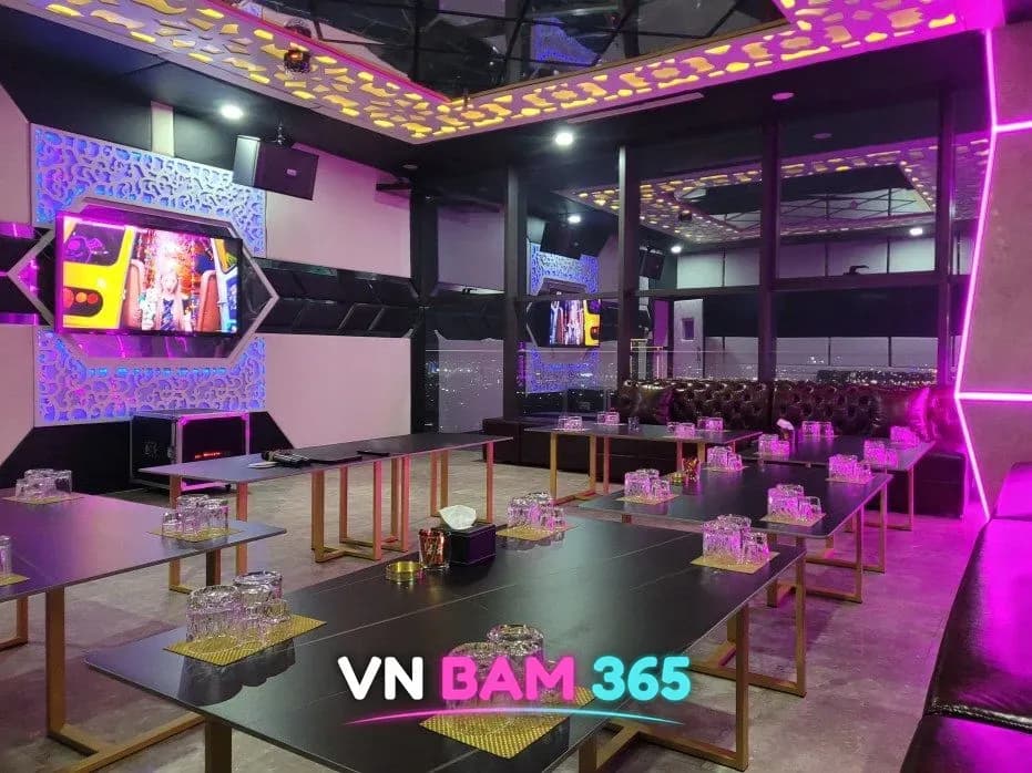 다낭 엑스바 단체석, 통창 너머 시내 야경과 긴 테이블, 벽면 TV와 조명 장식