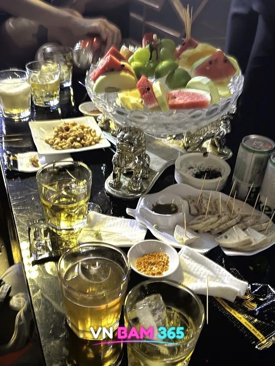 푸꾸옥 굿 클럽 테이블의 수박·포도 과일 플래터, 땅콩 안주와 위스키 하이볼 잔