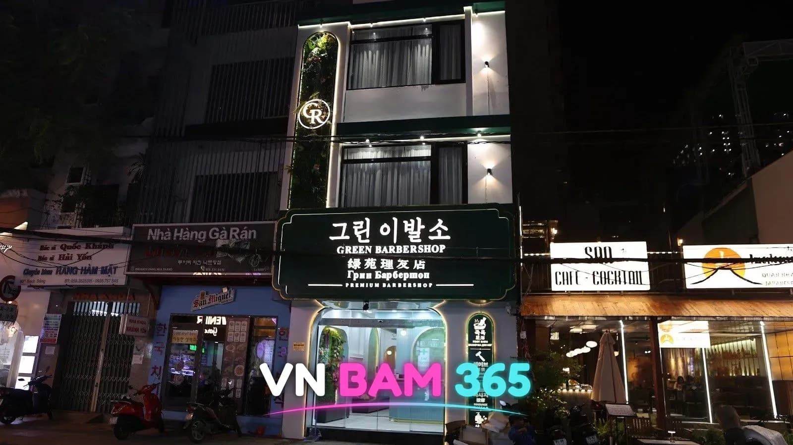 나트랑 그린 이발소 야간 외관, 조명이 켜진 녹색 간판과 유리 출입구