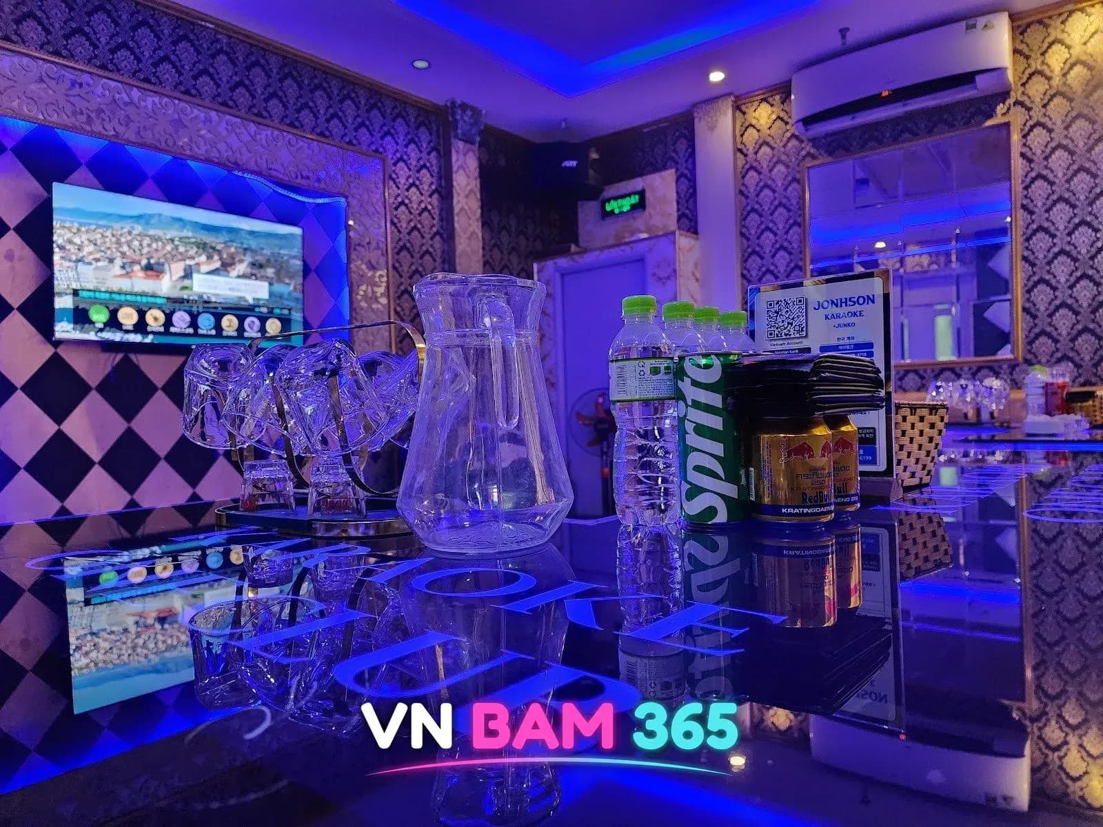 하노이 존슨 가라오케 룸, 노래방 화면과 체크무늬 벽, 테이블 위 음료와 유리잔