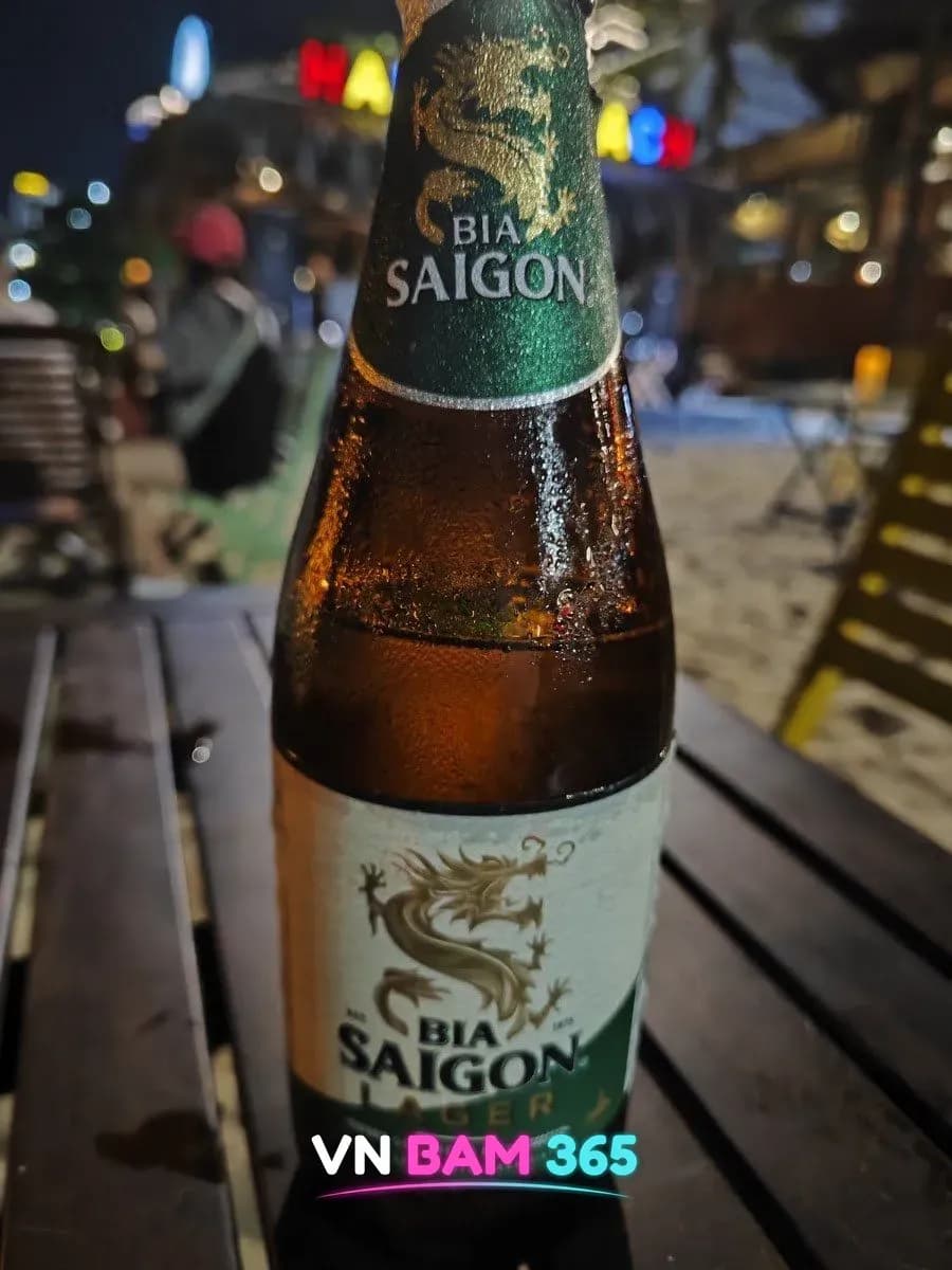 나트랑 해피 비치 해변 나무 테이블 위 사이공 라거 병맥주, 야간 해변 바 배경