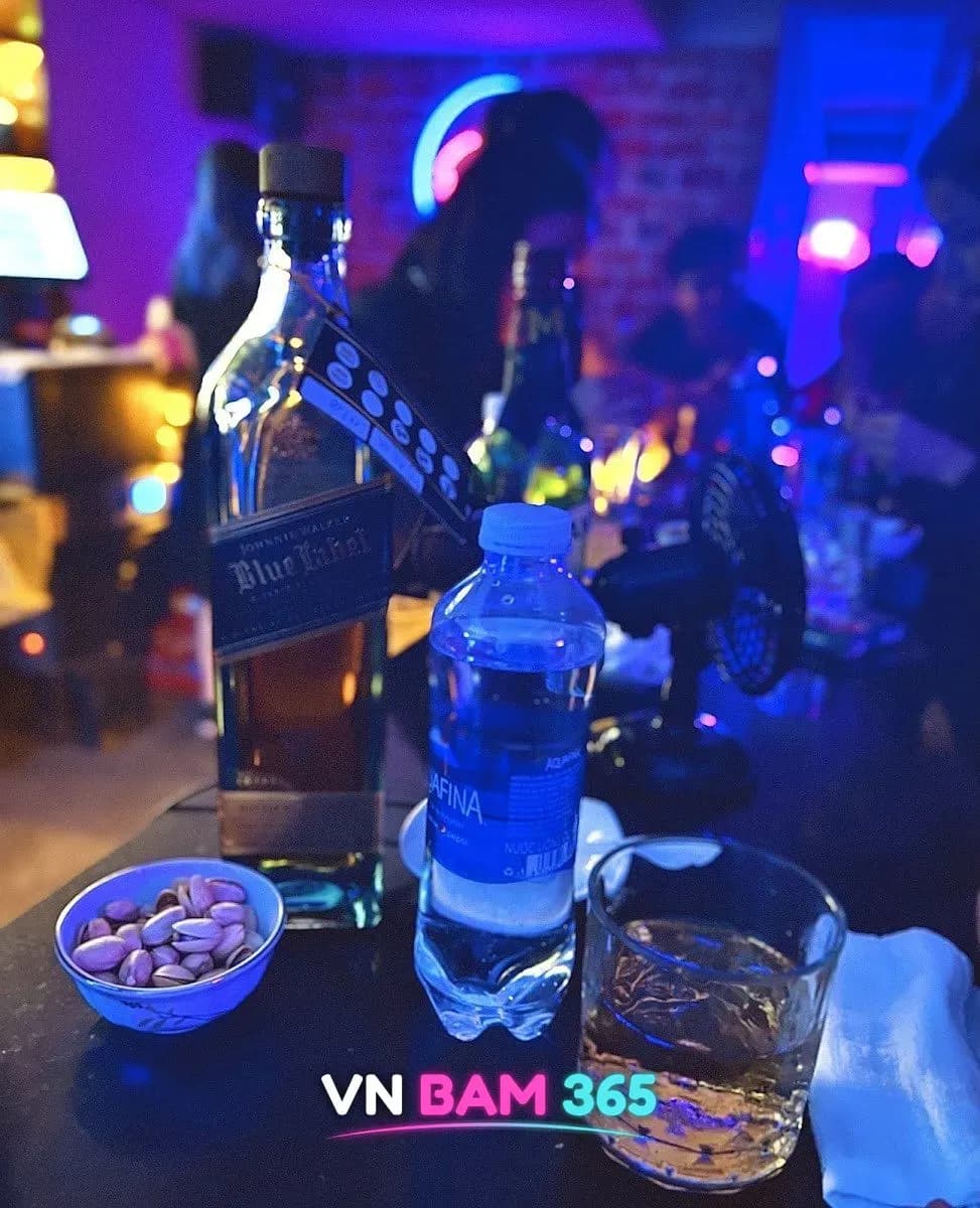 호치민 돌하우스 바 테이블 위 조니워커 블루라벨 병과 위스키 잔, 생수, 피스타치오 그릇