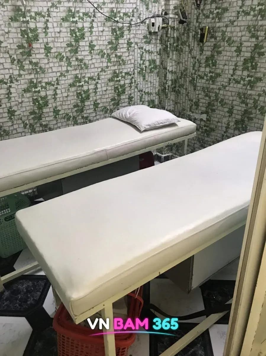 나트랑 화다우 마사지 2인 룸, 담쟁이 무늬 벽지 앞에 흰 마사지 베드 두 개