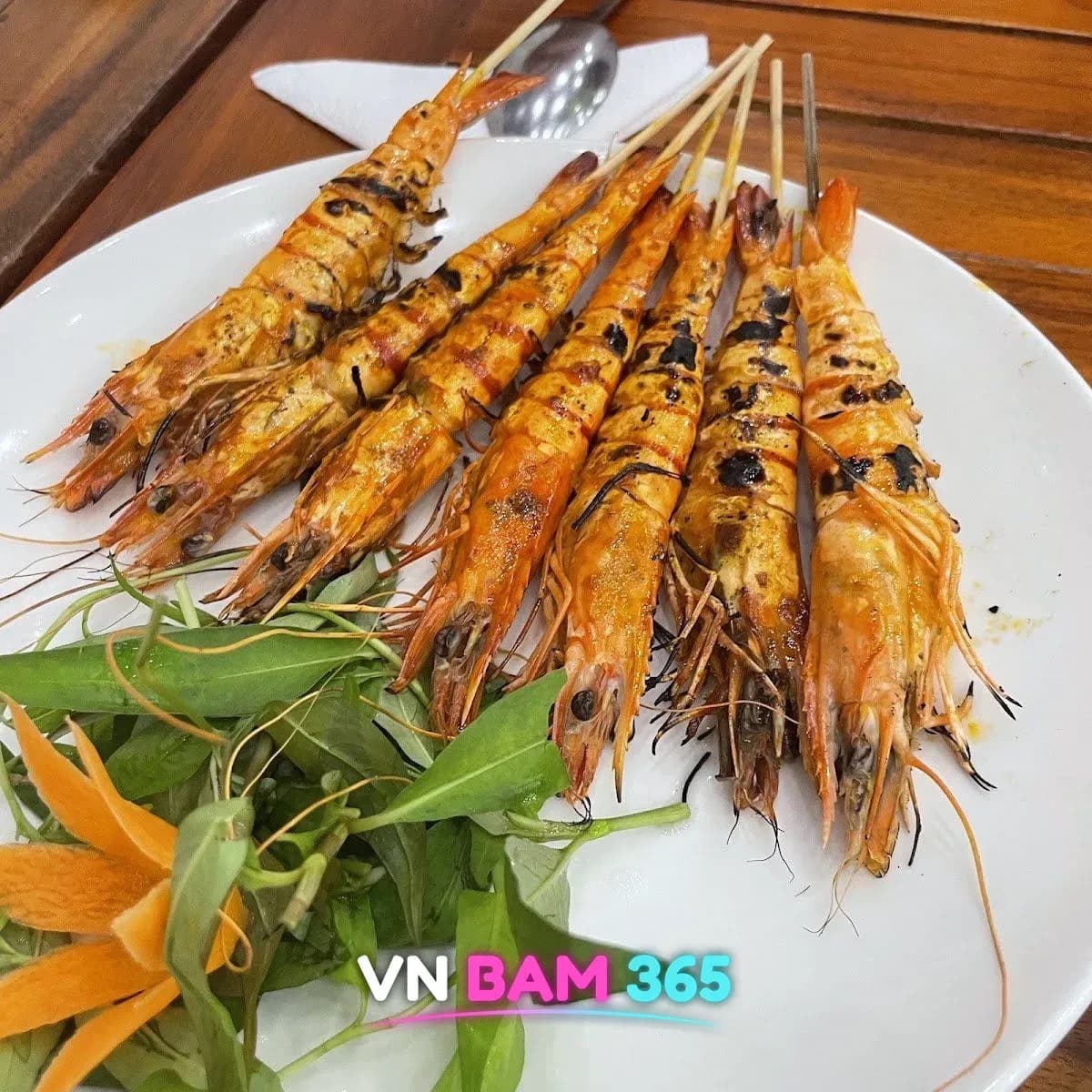 나트랑 JJ 씨푸드 새우 꼬치구이, 흰 접시에 양념 구운 새우 7마리와 채소