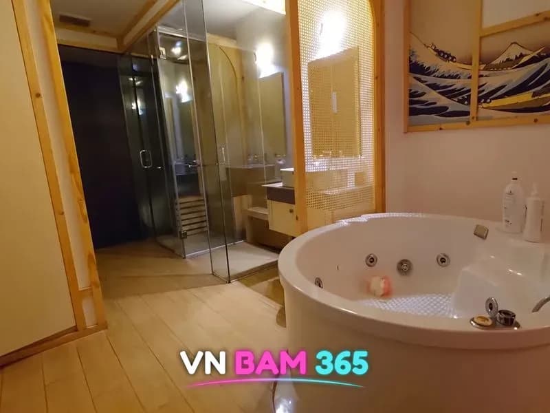 린체리 스파 객실 안 원형 월풀 욕조와 유리 샤워부스, 벽에 걸린 일본풍 파도 그림