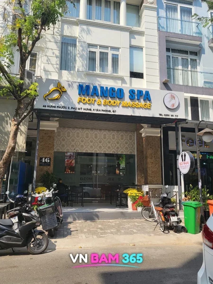 호치민 7군 푸미흥 망고 스파 외관, MANGO SPA 간판과 1층 유리 입구, 앞 인도에 오토바이
