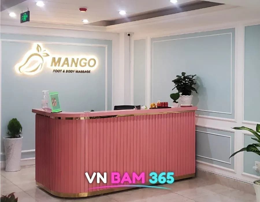 호치민 7군 망고 마사지 리셉션 데스크, 분홍 카운터 뒤 MANGO 조명 로고