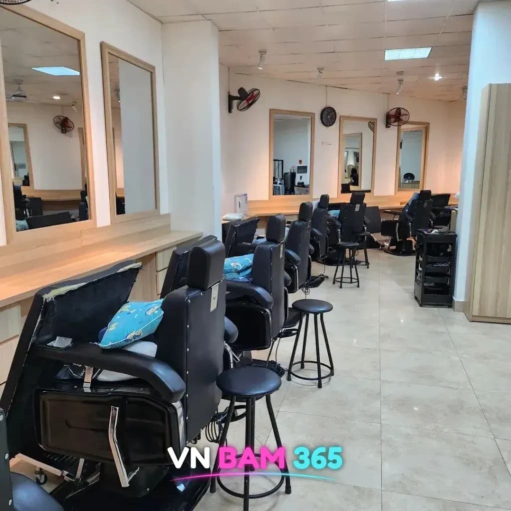하노이 미딩 이발소 실내, 나무 테두리 거울 앞에 줄지어 놓인 검은 이발 의자와 원형 스툴
