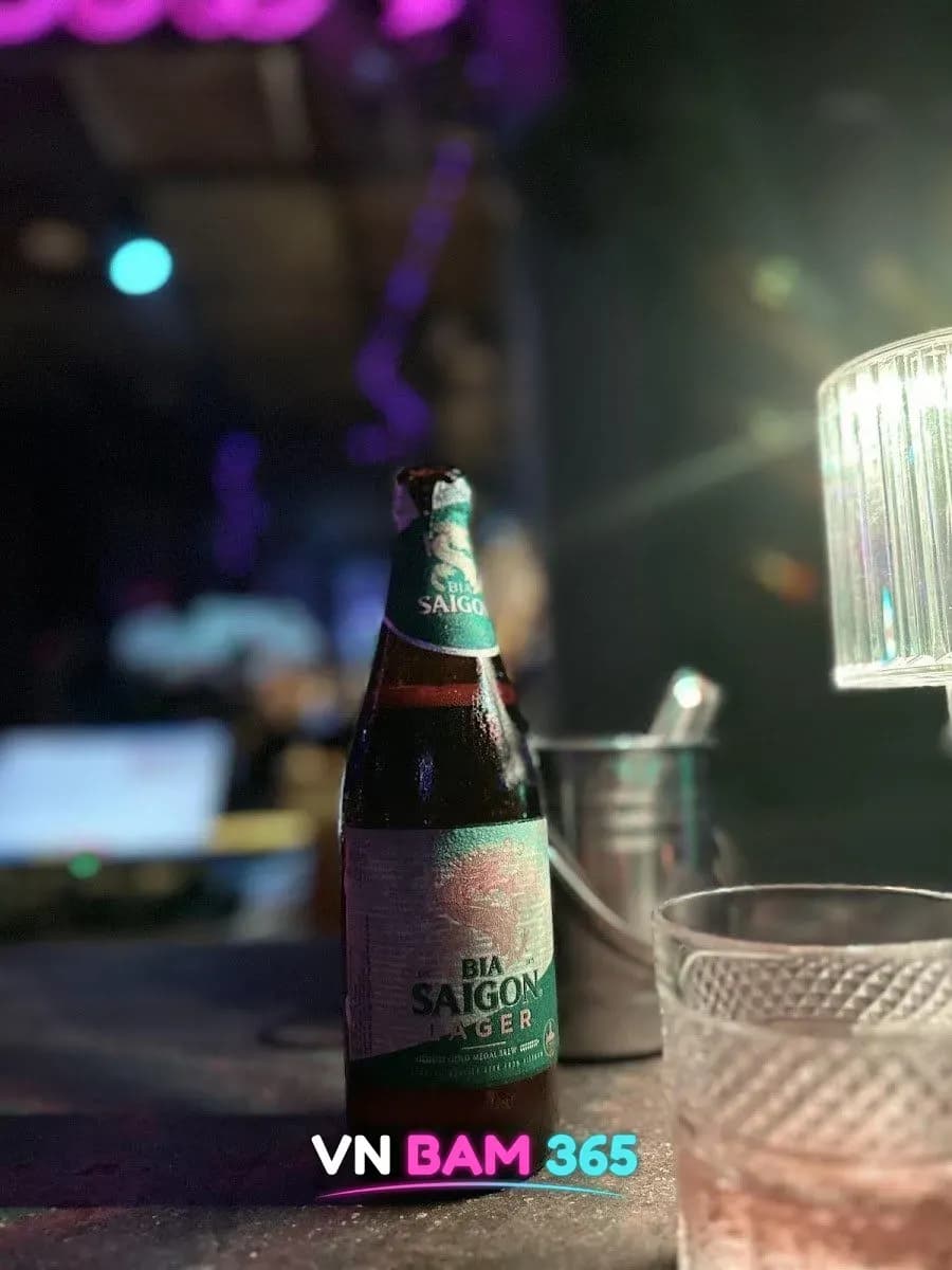 나트랑 NHA 바 테이블 위 사이공 라거 병맥주와 얼음 버킷, 핑크 네온 조명 배경