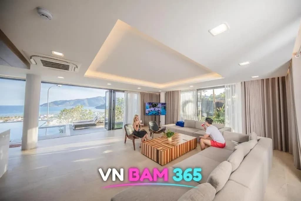 나트랑 해변 풀빌라 예시, 바다와 산이 보이는 통창 거실, 대형 소파와 원목 테이블