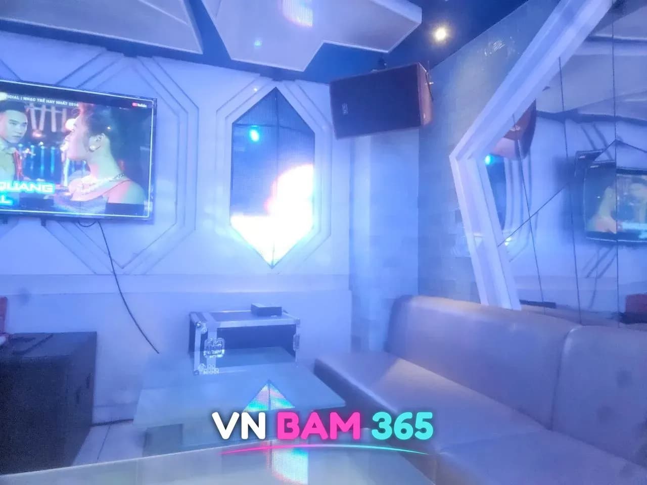 나트랑 퀸터 가라오케 룸, 흰 기하학 패널 벽과 대형 TV, 회색 소파