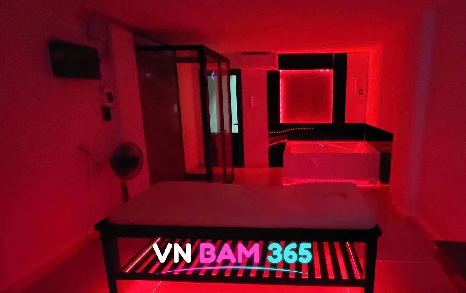 나트랑 사쿠라 마사지 룸, 마사지 베드와 유리 사우나 부스, 안쪽 욕조가 붉은 조명 아래 보이는 실내