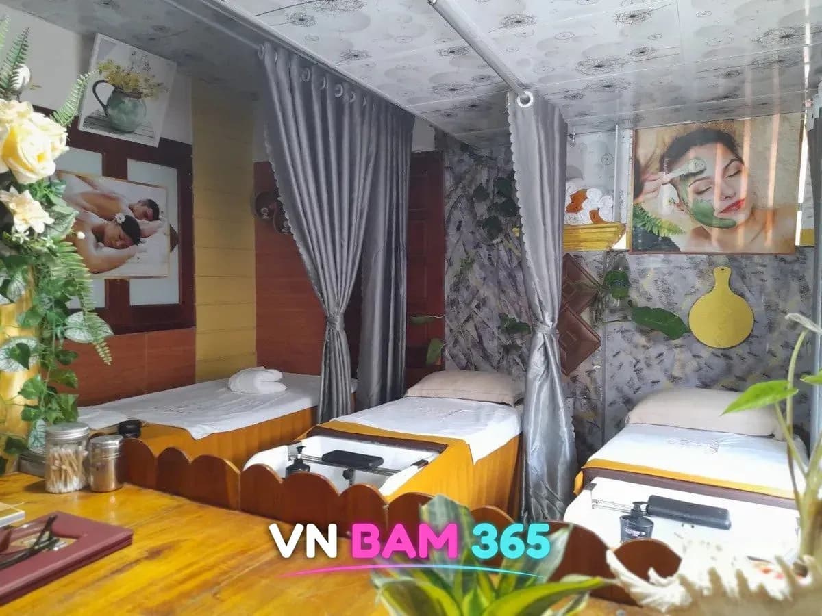 푸꾸옥 보니3 VIP 마사지 객실, 회색 커튼으로 나뉜 마사지 베드 3개와 원목 벽, 꽃 장식과 스파 포스터