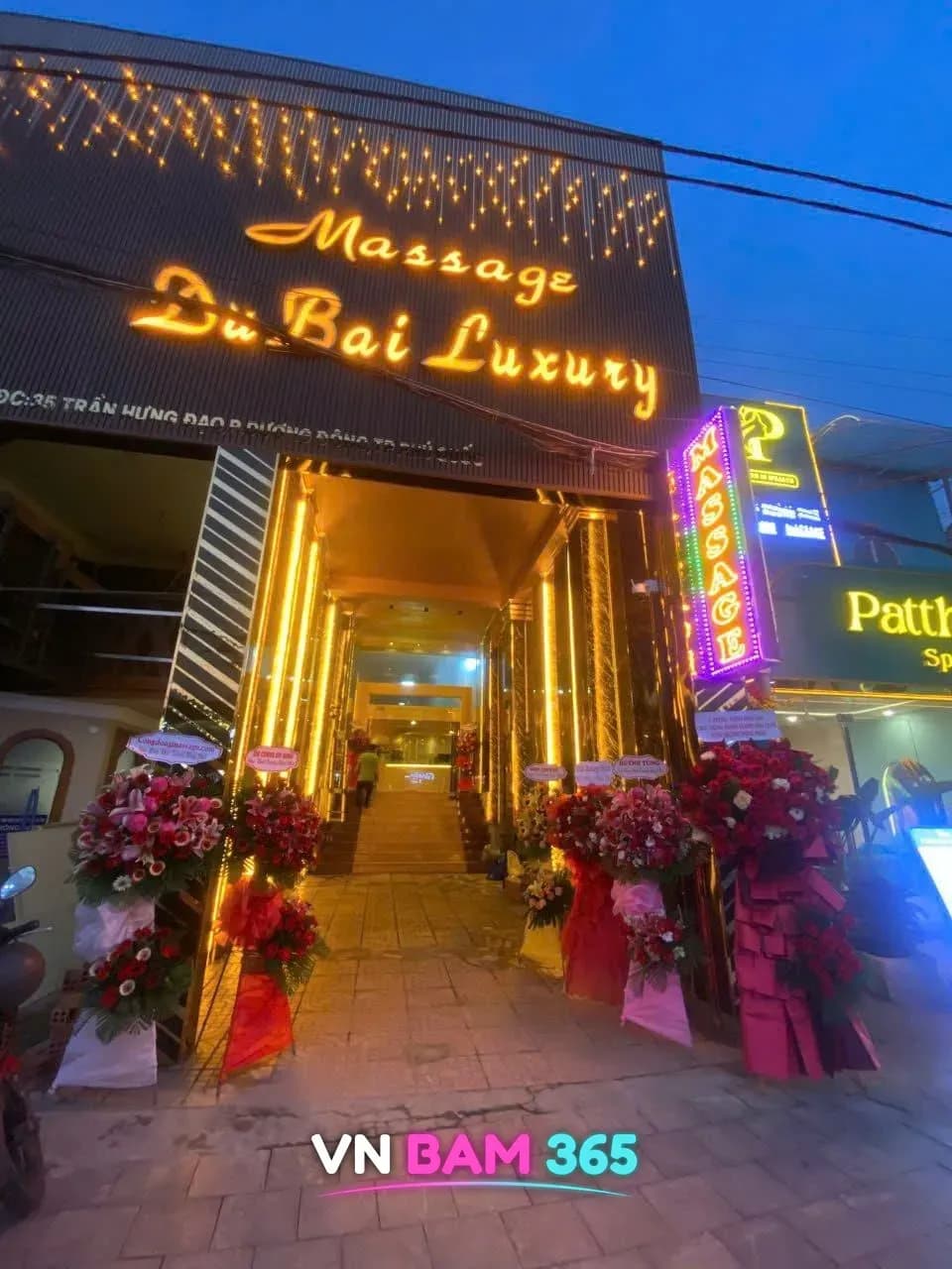 푸꾸옥 두바이 마사지 야간 입구, Massage DuBai Luxury 금색 간판과 조명 계단, 개업 화환