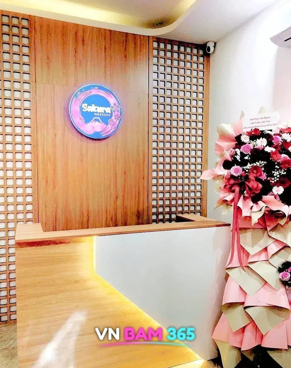 푸꾸옥 사쿠라 마사지 리셉션, 원목 격자 벽의 Sakura Massage 로고와 데스크, 개업 화환