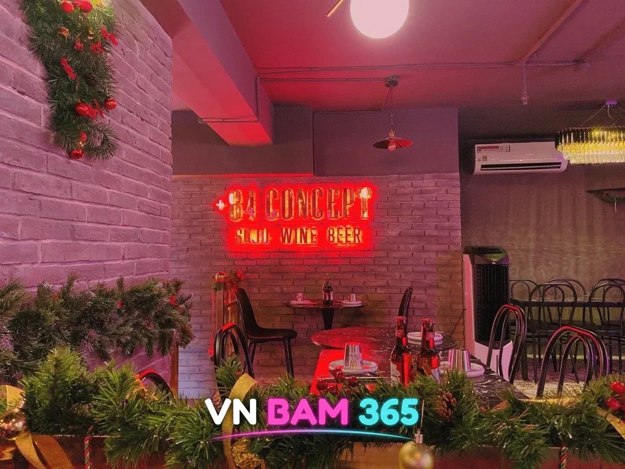호치민 84콘셉트 바 홀, 붉은 '+84 CONCEPT SOJU WINE BEER' 네온 간판과 벽돌 벽 테이블석