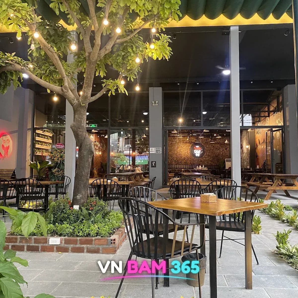 나트랑 씀모이 가든 정원 테라스석, 전구 조명 나무 아래 철제 의자와 안쪽 실내 홀