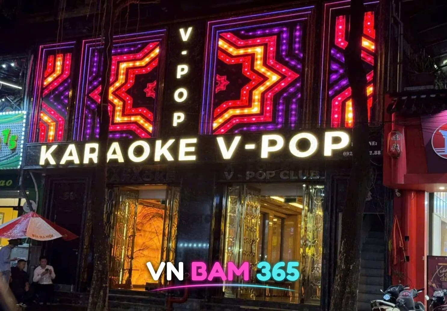 하노이 브이팝 가라오케 야간 외관, KARAOKE V-POP 조명 간판과 금색 유리문 입구