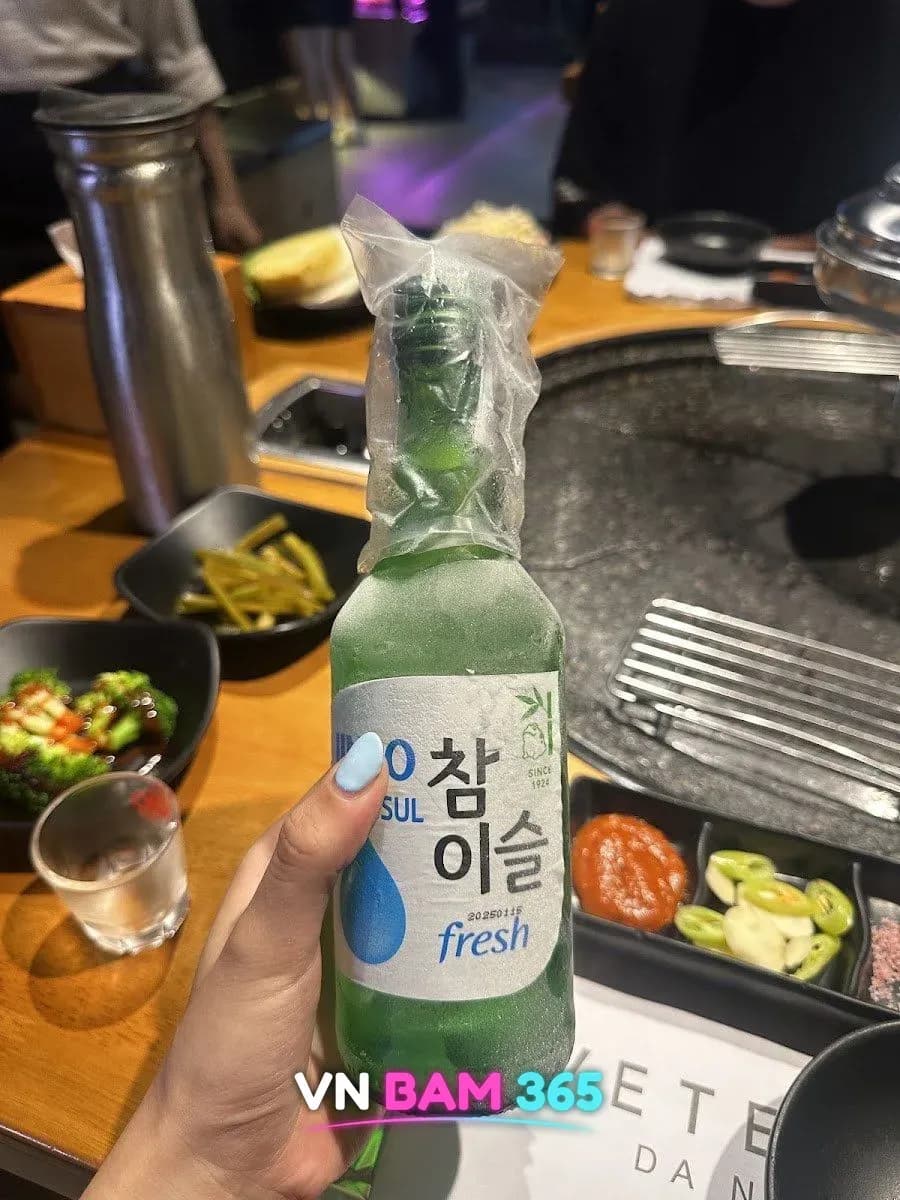 다낭 베테랑 레스토랑 테이블에서 든 참이슬 소주병, 뒤로 돌판 그릴과 반찬