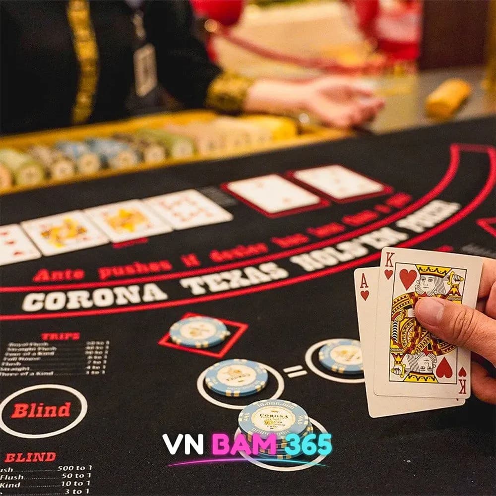 푸꾸옥 코로나 카지노 텍사스 홀덤 테이블 위 CORONA 칩과 에이스·킹 카드를 든 손