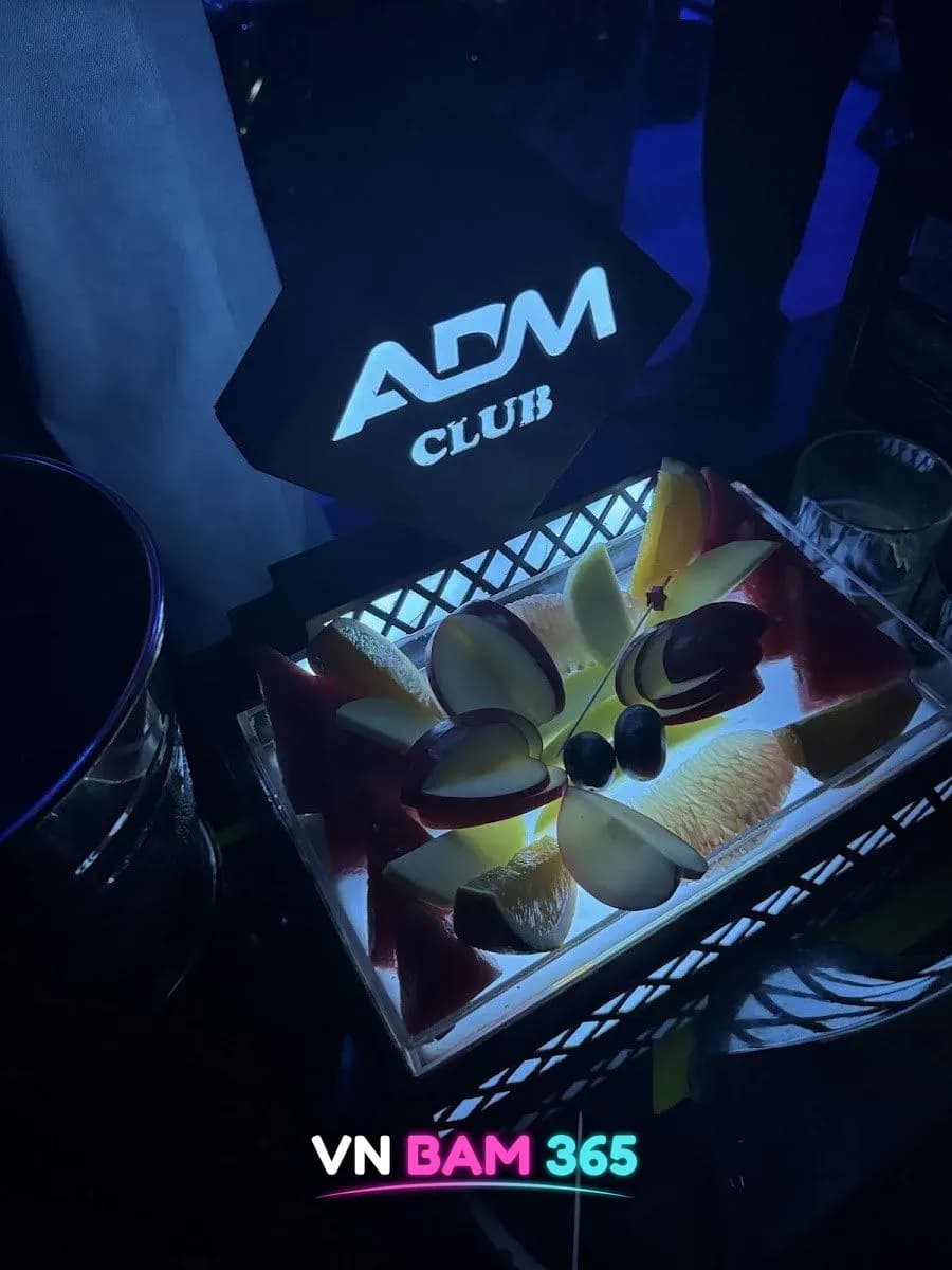 다낭 ADM 클럽 테이블, ADM CLUB 로고 판 아래 조명 트레이에 담긴 과일 모둠