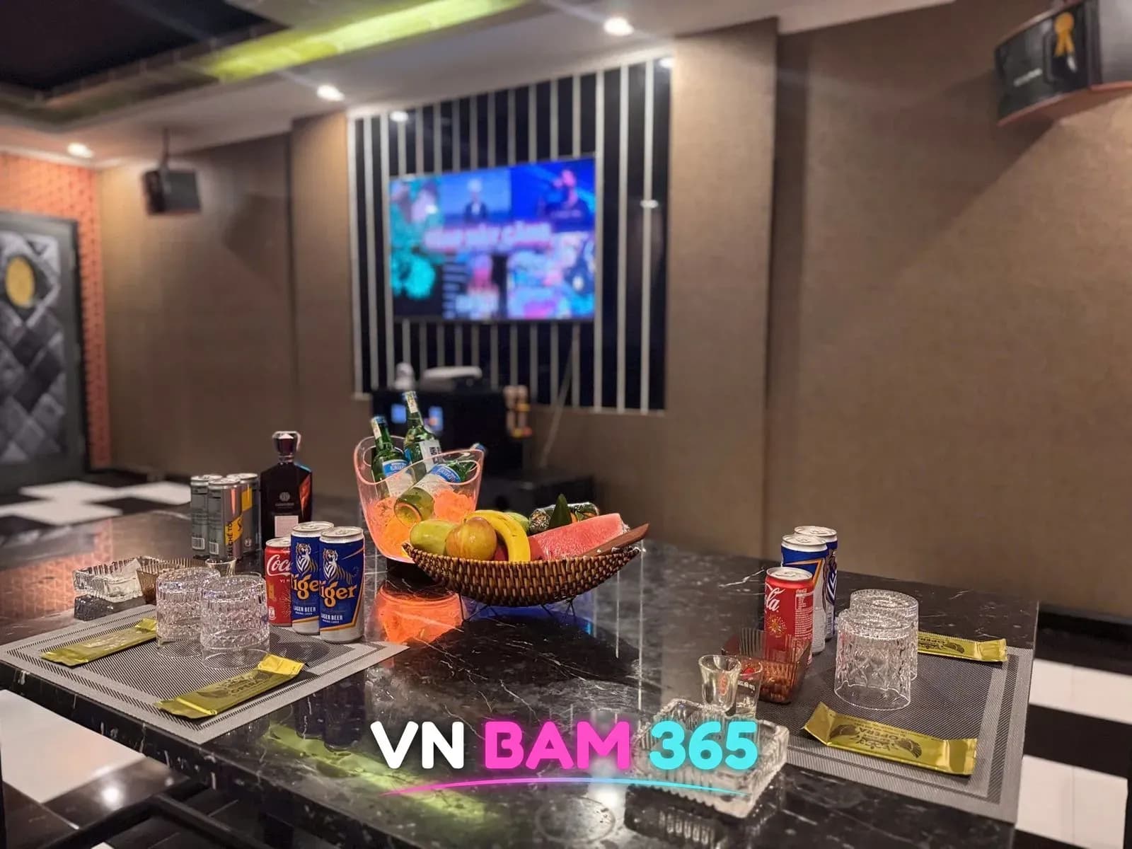 다낭 원오페라 가라오케 룸, 과일 바구니와 아이스버킷, 타이거·콜라 캔이 놓인 테이블과 뒤쪽 노래방 화면