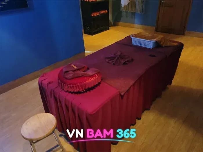 다낭 더킹스파 마사지 룸, 파란 벽과 나무 바닥에 붉은 커버를 씌운 마사지 베드와 원목 스툴