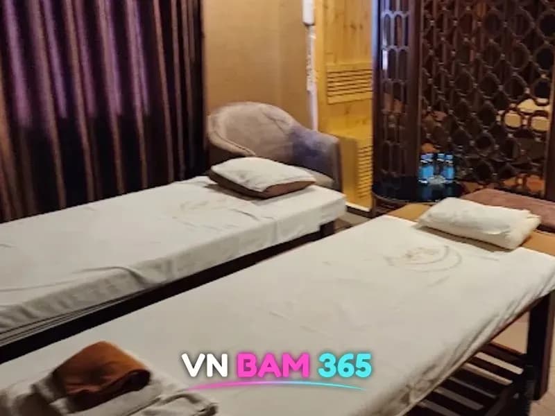 호치민 루나 마사지 2인 마사지 룸, 흰 시트를 깐 베드 두 개와 안락의자, 안쪽 원목 사우나