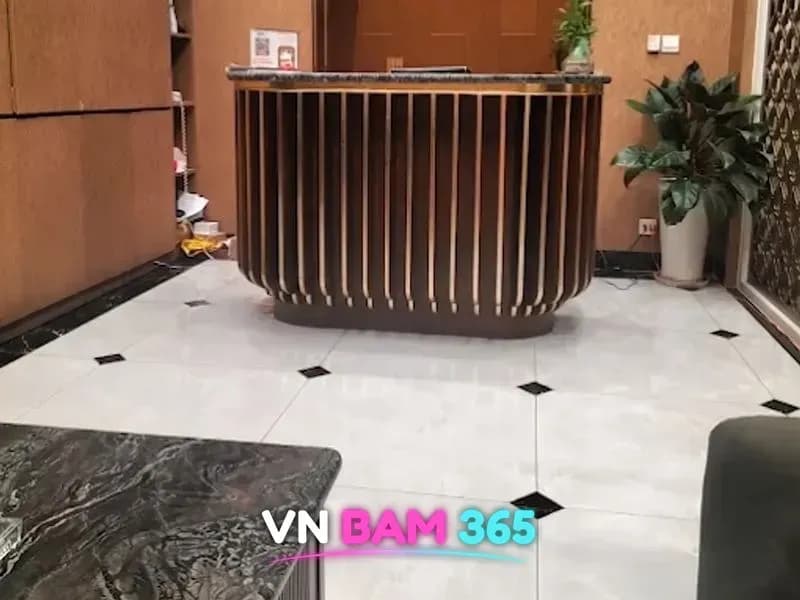 호치민 루나 마사지 리셉션, 원목 세로 루버 카운터와 흰 대리석 바닥, 화분