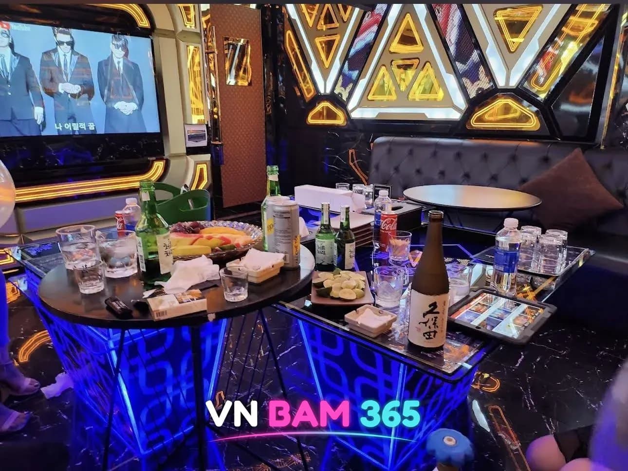 호치민 W 가라오케 룸 테이블에 차려진 소주·맥주와 안주, 뒤편 노래방 화면