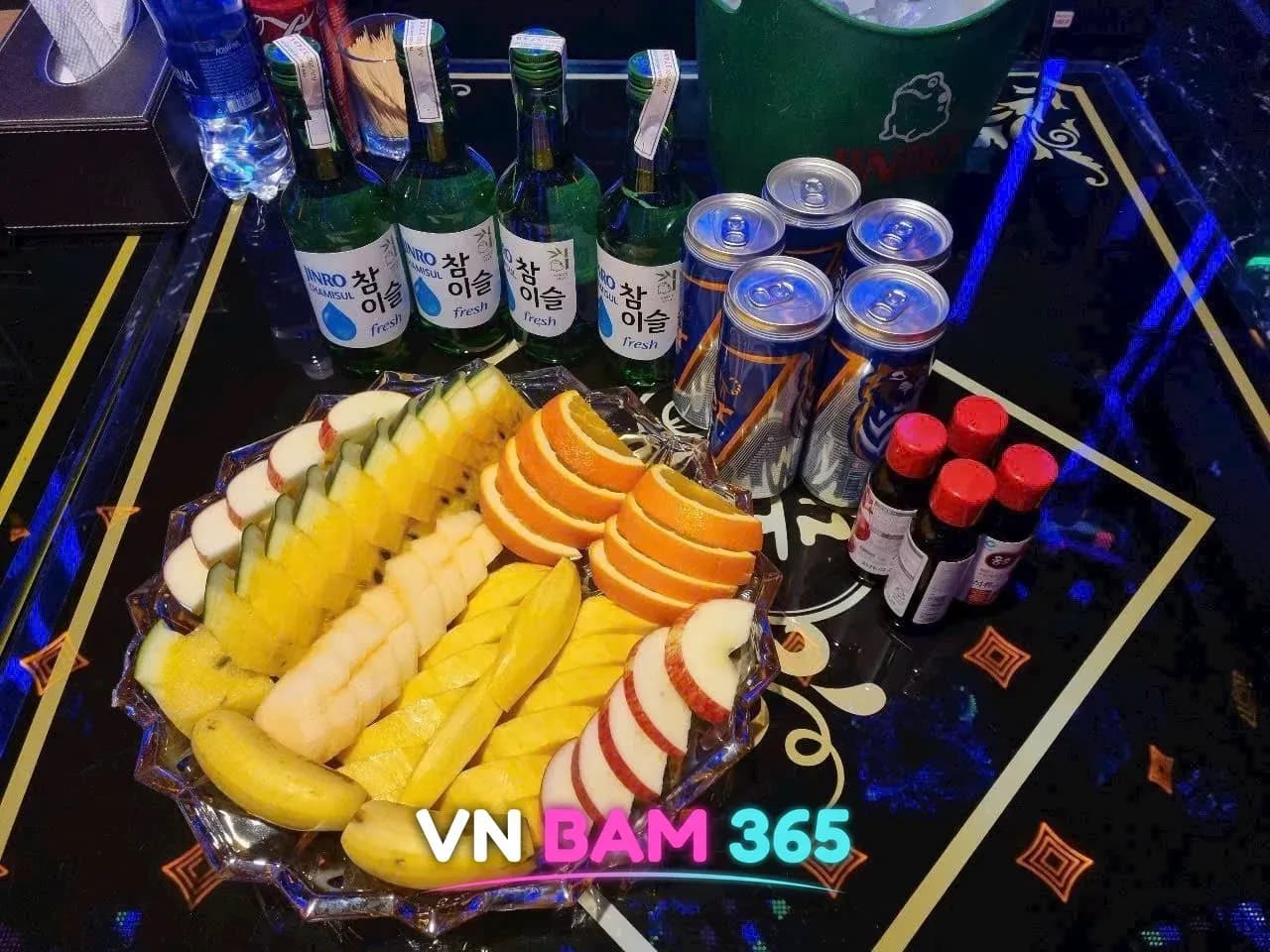 호치민 W 가라오케 테이블의 과일 안주 접시와 참이슬, 캔 음료