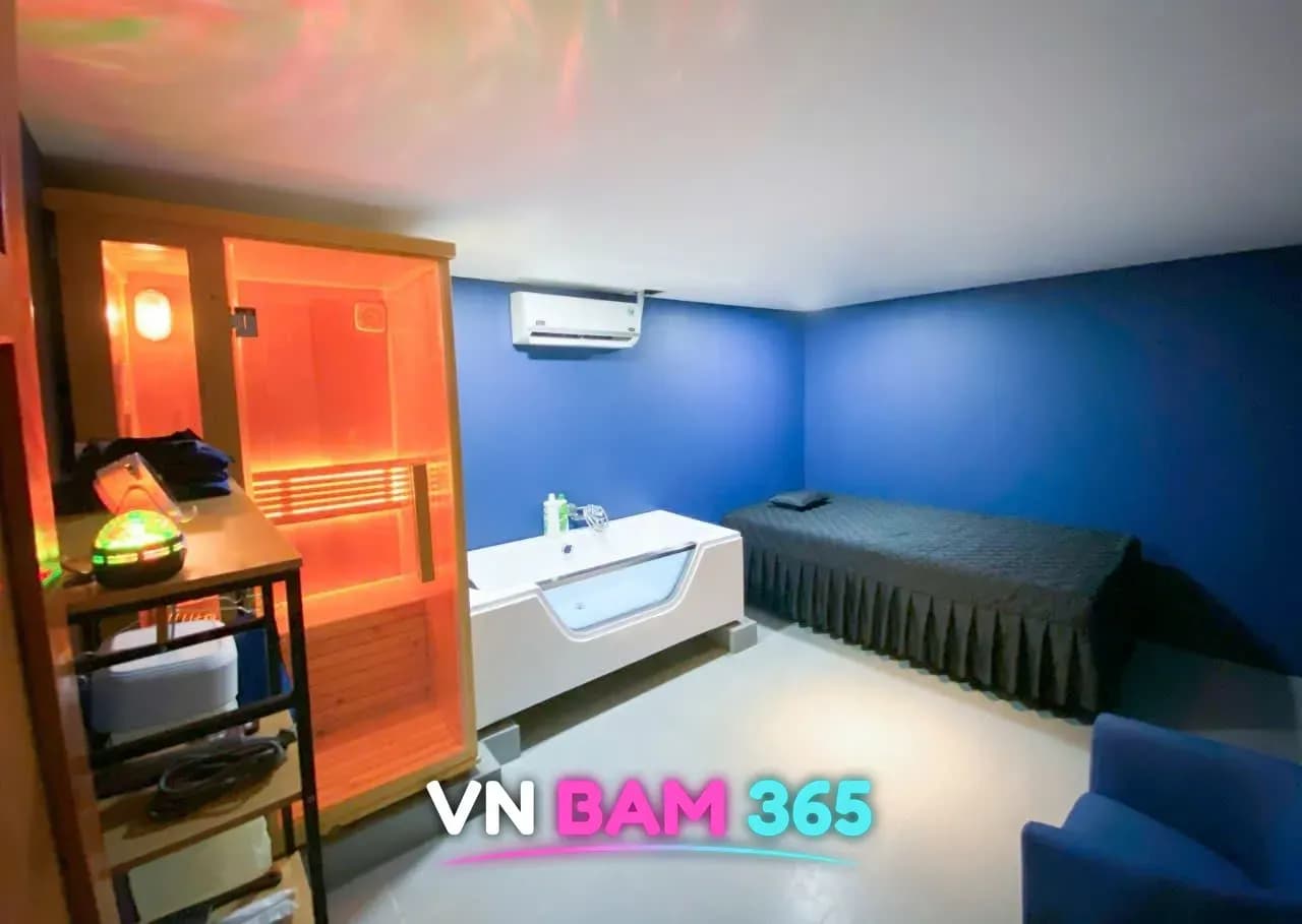 호치민 킹스톤 마사지 VIP룸, 파란 벽에 원목 사우나 부스와 유리창 욕조, 검은 퀼팅 마사지 베드