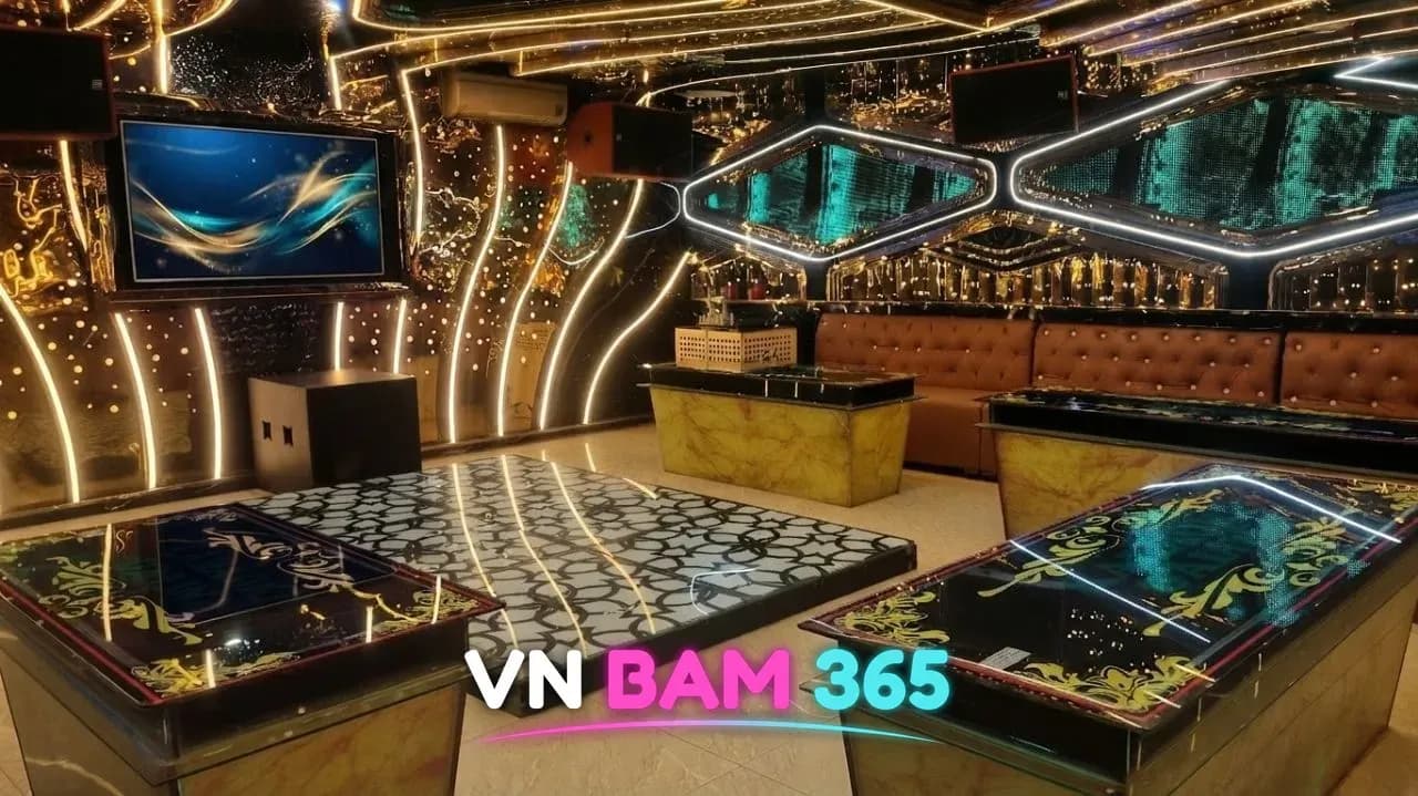 나트랑 갈리나 가라오케 룸, 금색 곡선 조명 벽과 가운데 무대 바닥, 양옆 유리 테이블과 가죽 소파