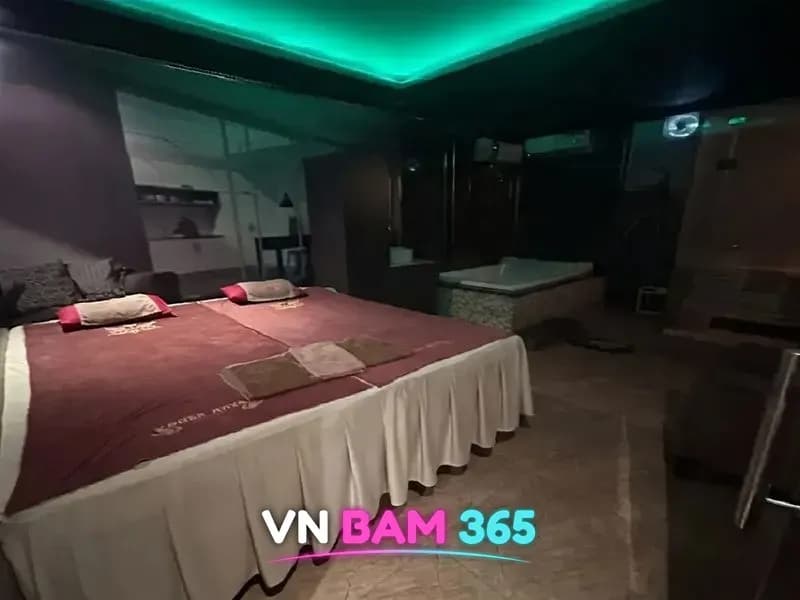 호치민 스타킹 마사지 개인실, 2인 마사지 베드와 욕조, 안쪽 사우나 부스가 있는 녹색 간접조명 룸