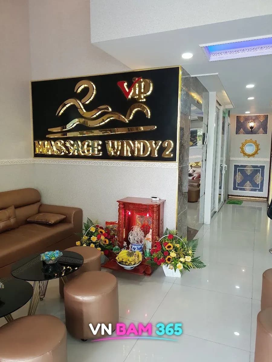 윈디2 마사지 로비, 벽면의 MASSAGE WINDY 2 금색 로고 간판과 가죽 소파, 꽃 장식